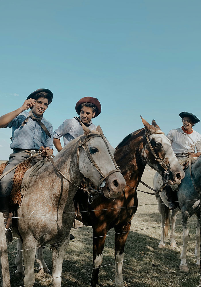 Three gauchos on horseback riding across the Uruguayan countryside.
