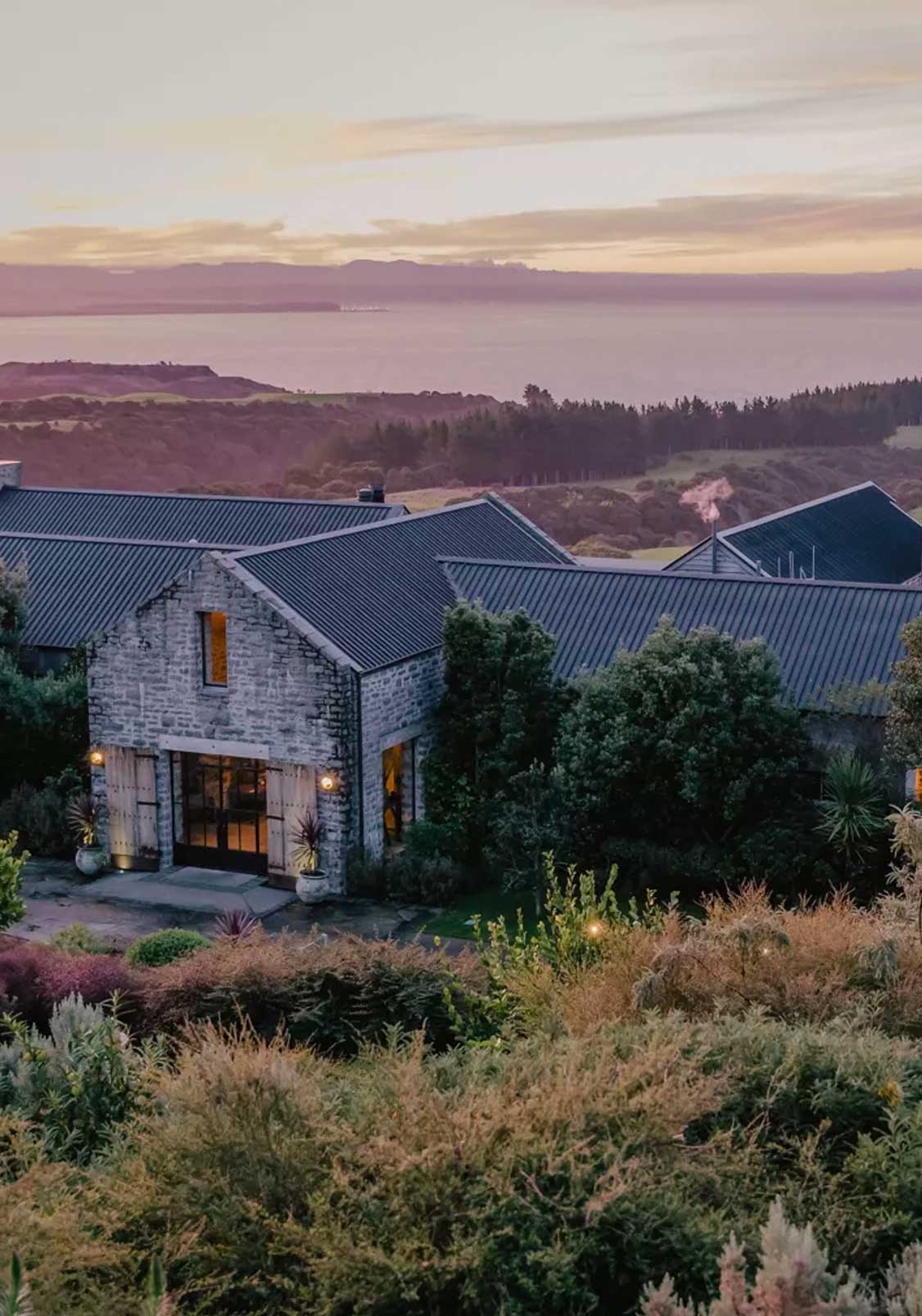 Large stone house on a hill overlooking the ocean at sunset, The Farm at Cape Kidnappers, Hawke's Bay, New Zealand.